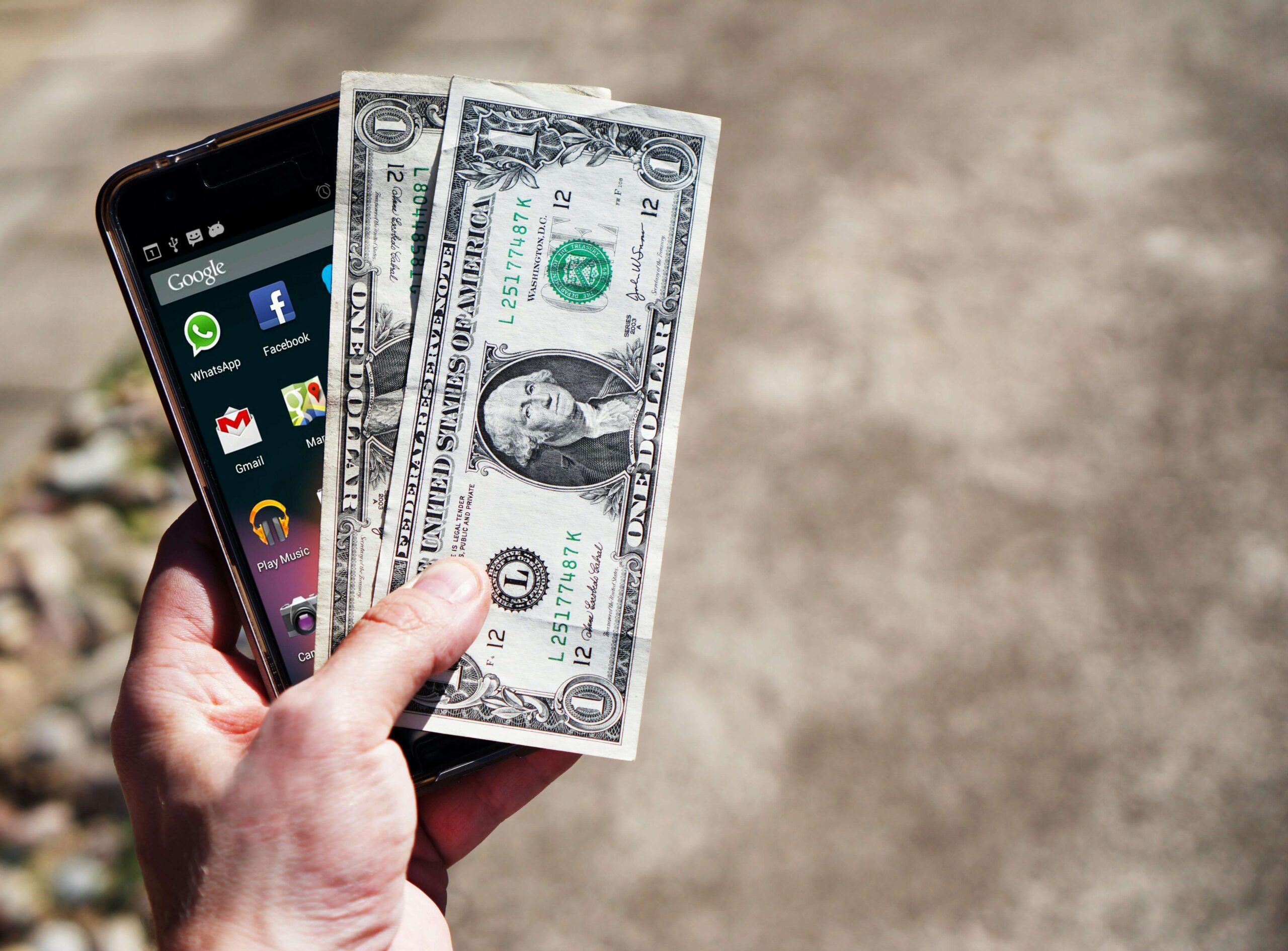 A man holding a phone and paper bills