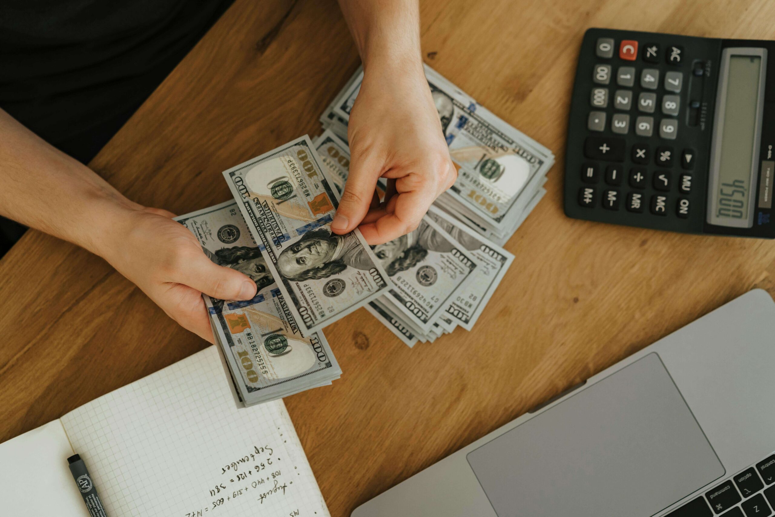 A man counting money while using a calculator